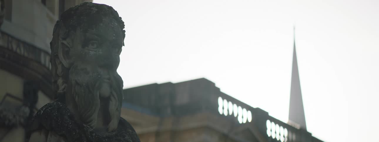 Close up of the head of a statue next to a spire or tower