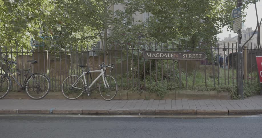 Suburban city street with two bicycles leaning against a fence