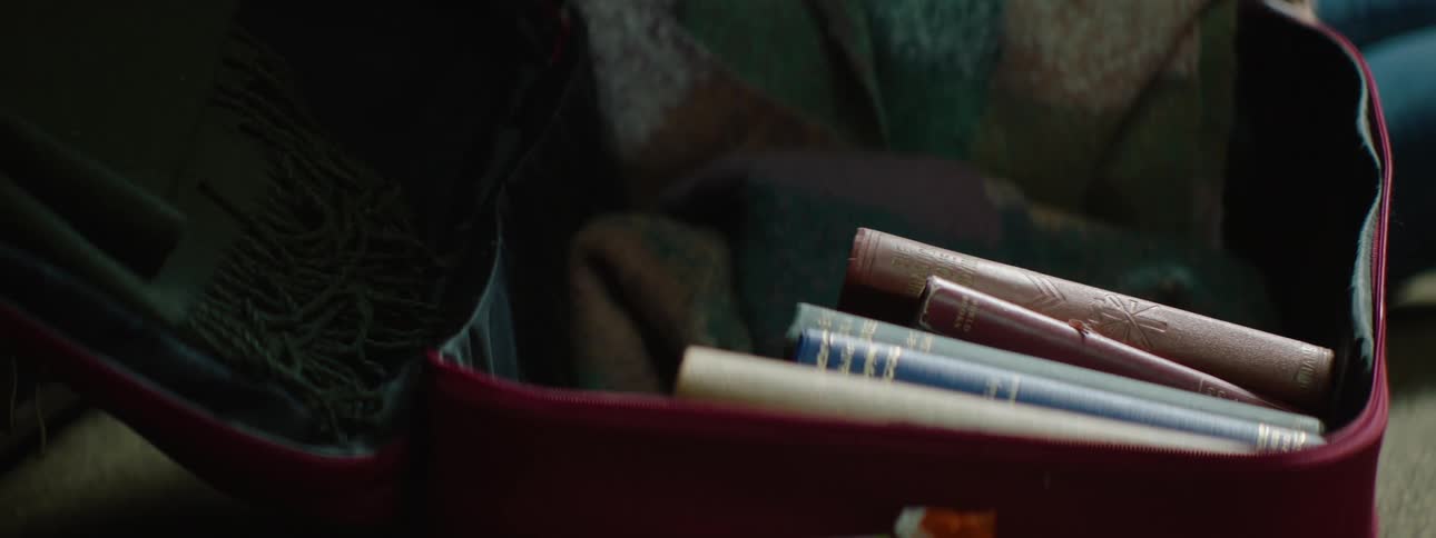 Womans hands taking books out of a suitcase