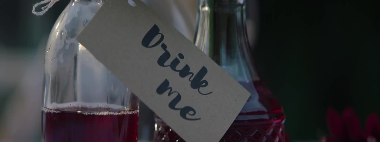 Two bottles of liquor with a drink me sign attached