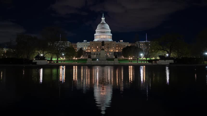 People walk around the capitol building at night