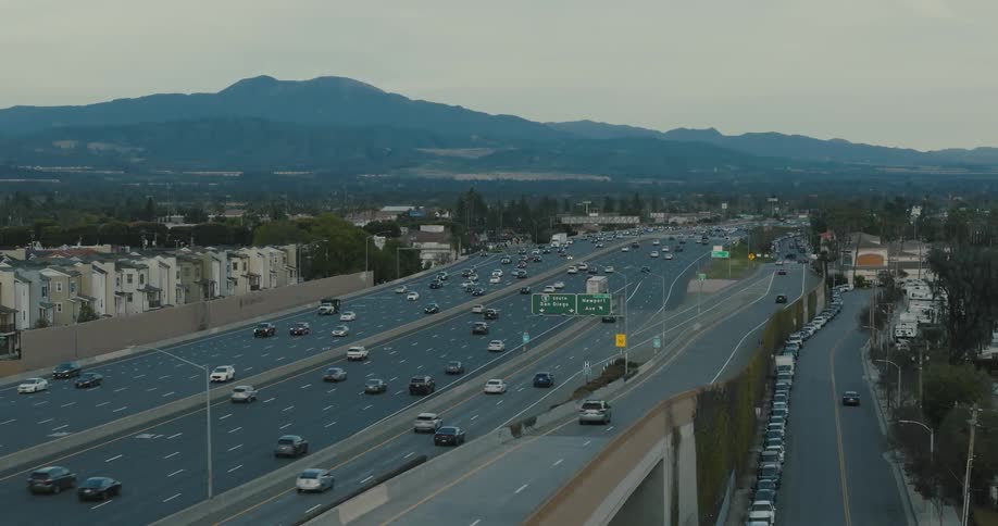 Cars drive down a city highway a mountain range visible in the distance