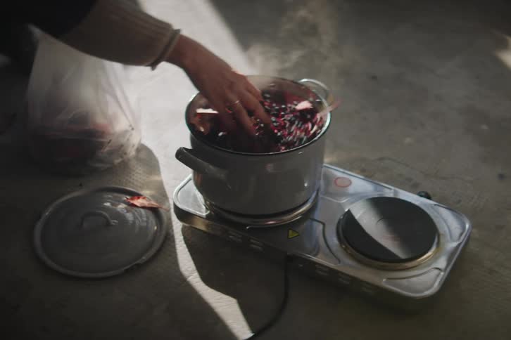 A person drops food into a steaming pot