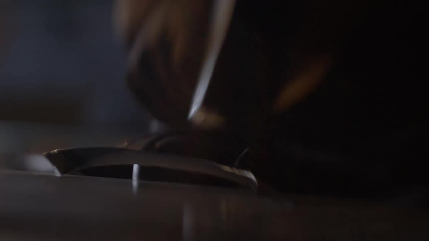 A worker taps a metal object with a heavy hammer