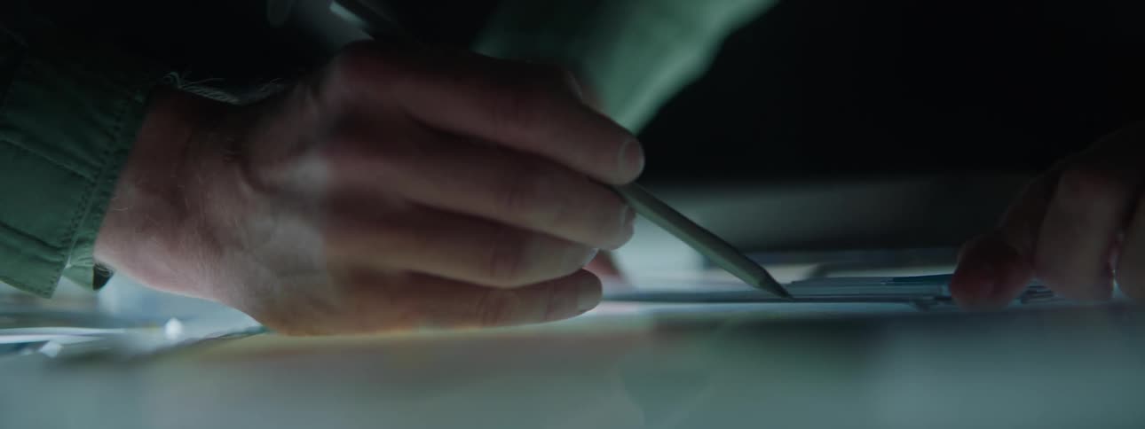 Hands of two men with one of them reviewing a document with a pen