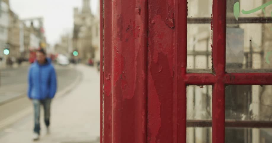 Street with a vintage telephone booth and people walking on the sidewalks in a city