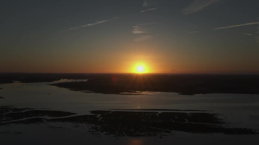 A sunset in a region with lots of water and some land around it
