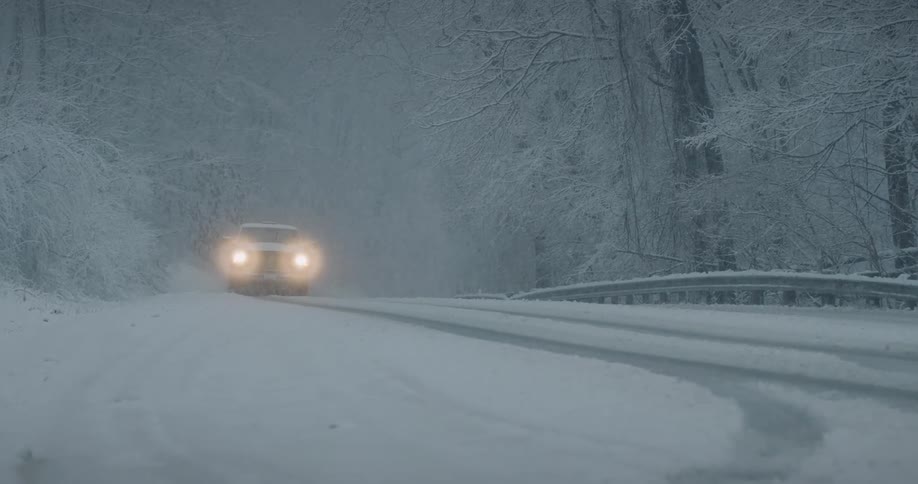 A truck drives down a snow covered road