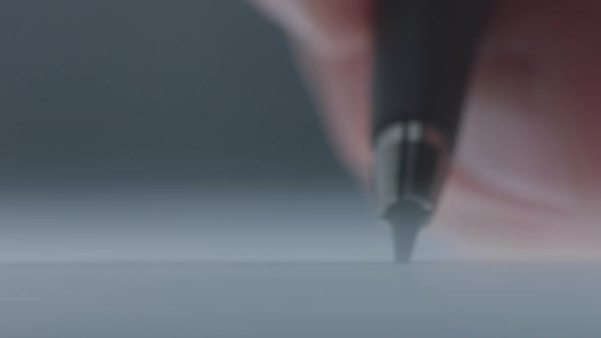 A human finger holding a black pen and swiping across a white paper surface