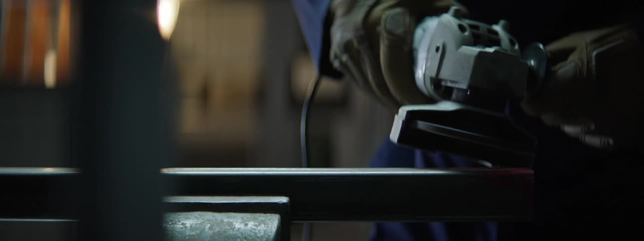 Focus on a persons hand wearing protective gloves sawing a metal sheet