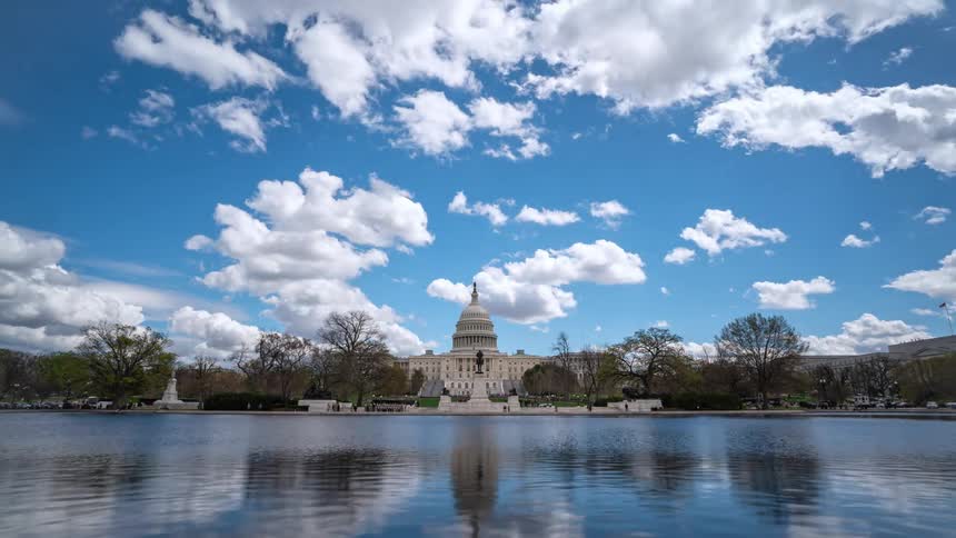 Panorama of the washington capitol in front of a lake during the day with clouds passing by in time lapse