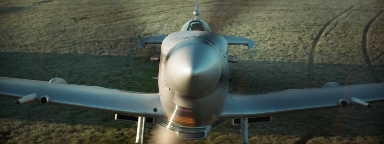 Front part of a singleengine plane parked in a pasture with the propeller moving