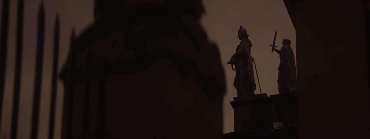 Sculpture monuments with sword and bow on a religious tower at night