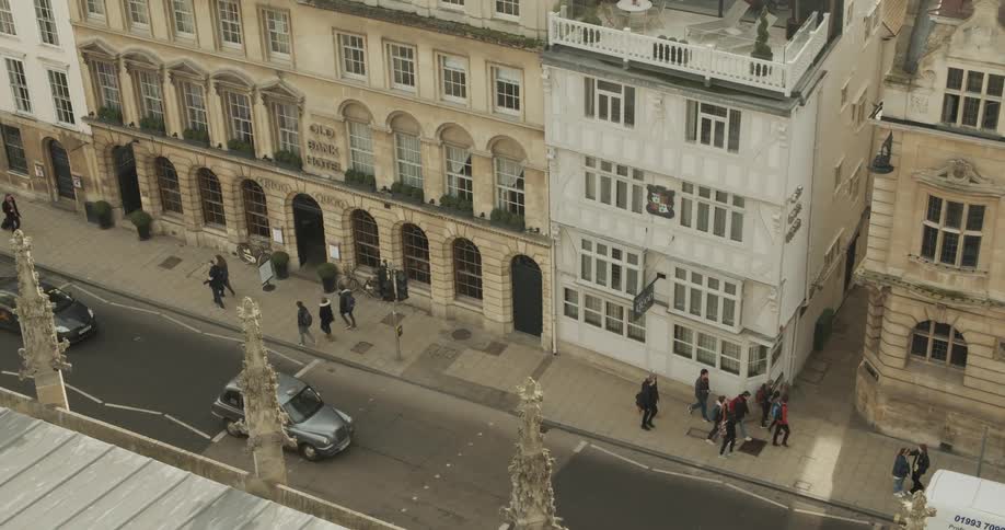 People walk on sidewalks as cars drive by in the street