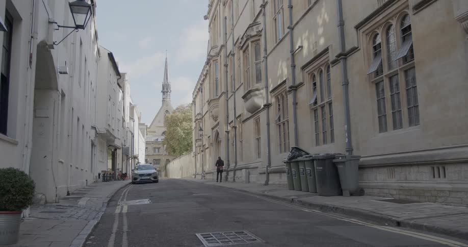 Street of a narrow suburban city with a pedestrian and a cathedral in the background
