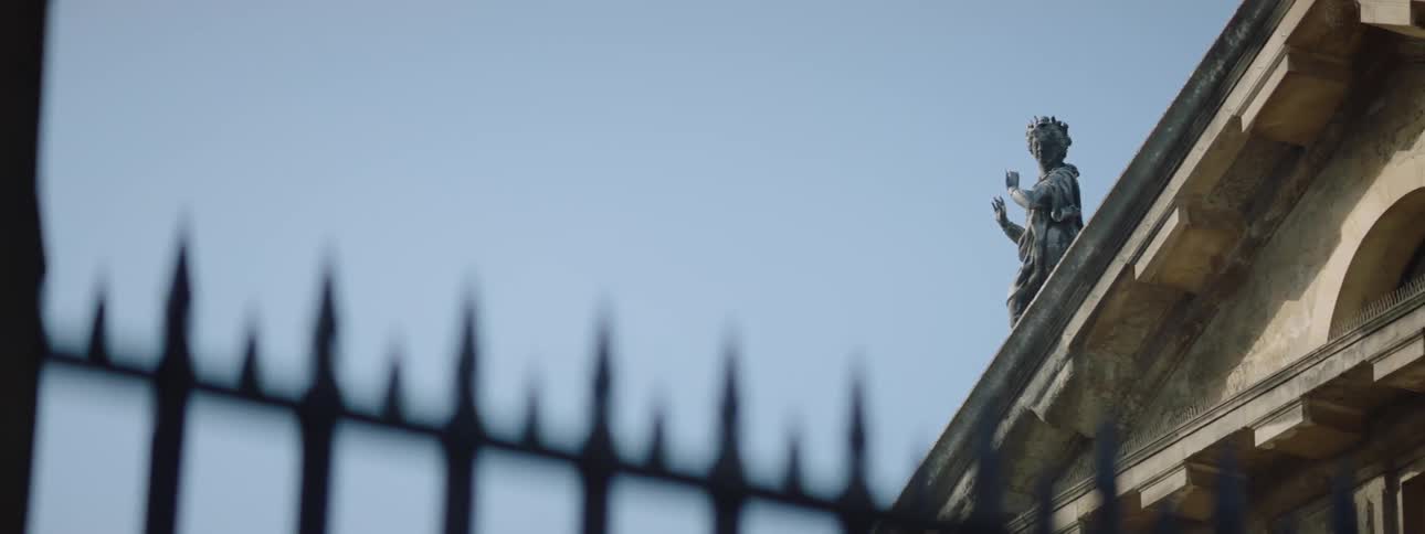 A statue of a woman with flowing robes stands on top of a building
