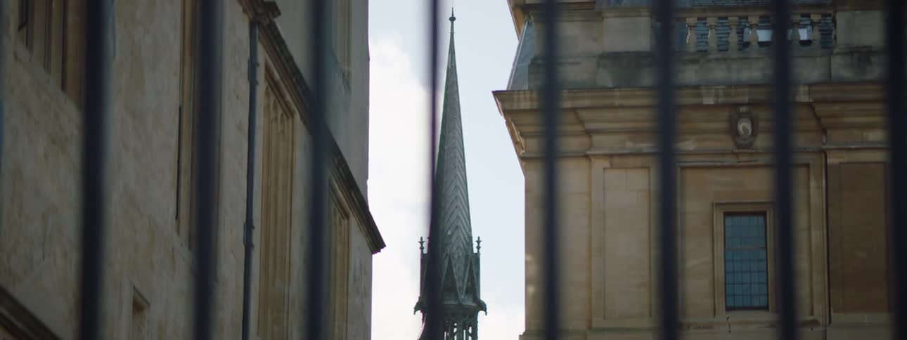 A huge tower of gothic architecture that stands among more recent buildings