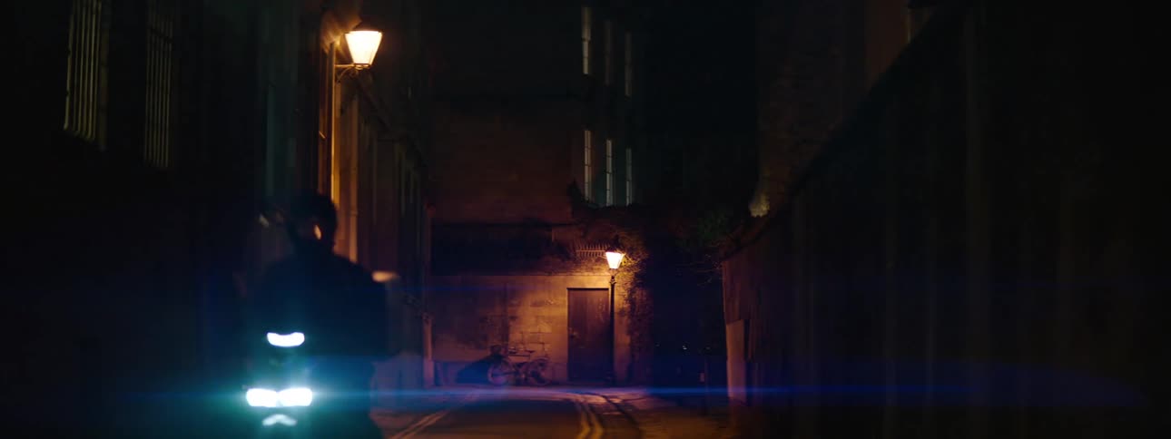 Alley of a suburban city at night with a motorbike passing by