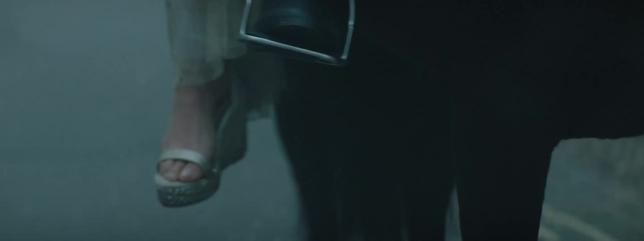 Close up of the feet of a woman riding a horse in the mist