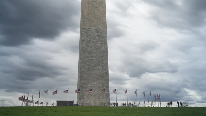 Washington monument with pedestrians passing by and on a cloudy day