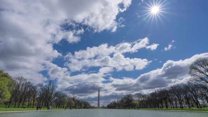 Time lapse of the washington monument bathed in sunlight breaking through clouds