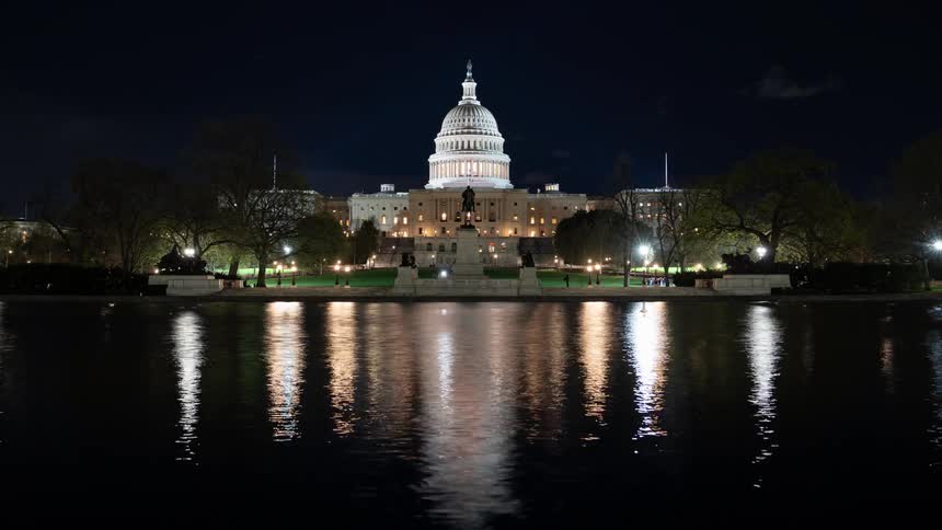 United states capitol seen at night in front of a lake and in time lapse
