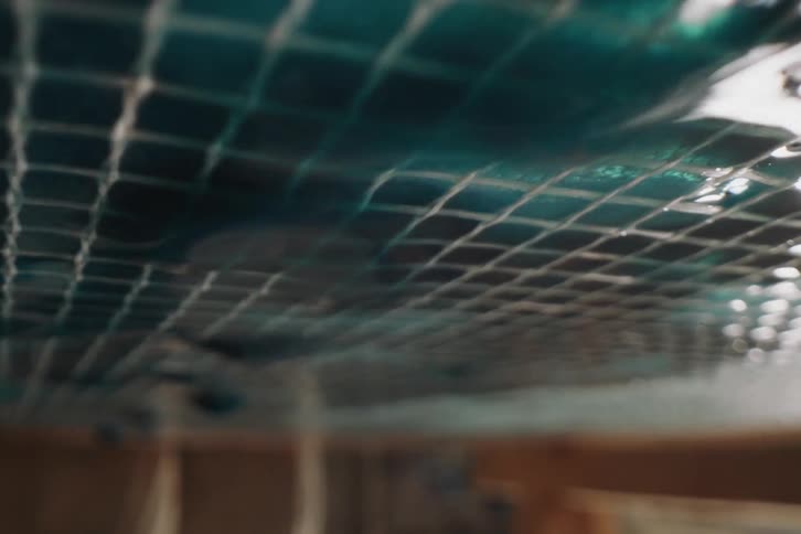 Extreme closeup on an extensive sieve with drops of blue liquid falling