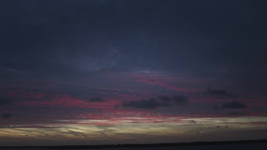 Landscape in a purplecolored morning sky under a field on a lake