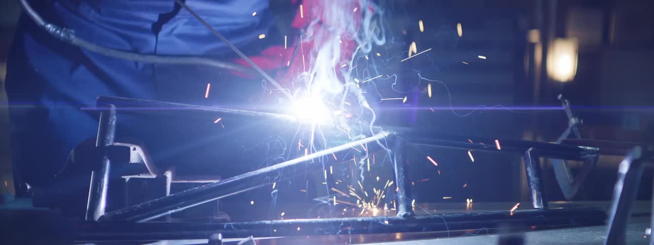 Person with mask and protective gloves welding on a metal cylinder