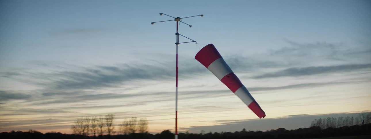 Windsock in a natural environment with the silhouette of mountains and trees on the horizon on a morning