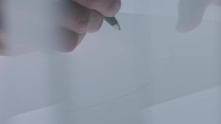 Extreme closeup of a persons hands drawing at a table under illuminated with white light