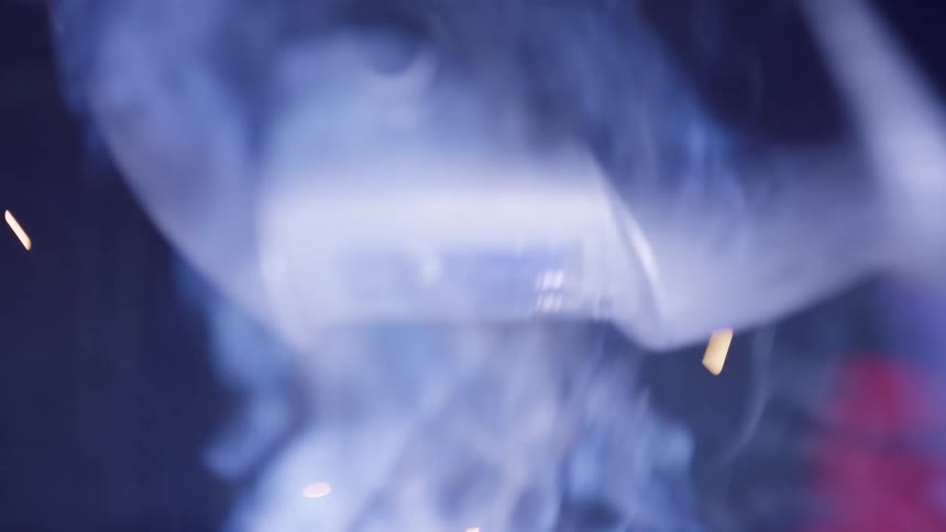 A man is welding a piece of metal in a dark workshop