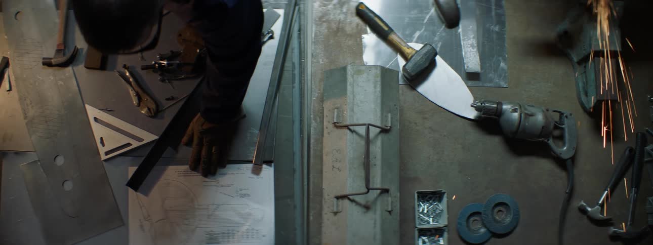 Table with tools and metal with a man observing a project