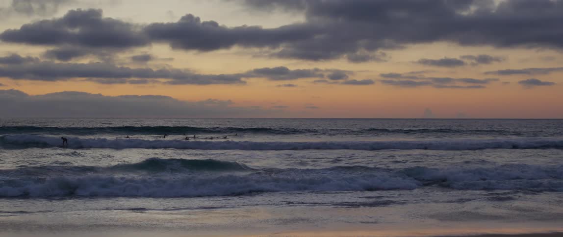 Slow motion footage of waves crashing on a beach at sunset