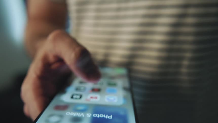 A male swipes and taps his smartphone