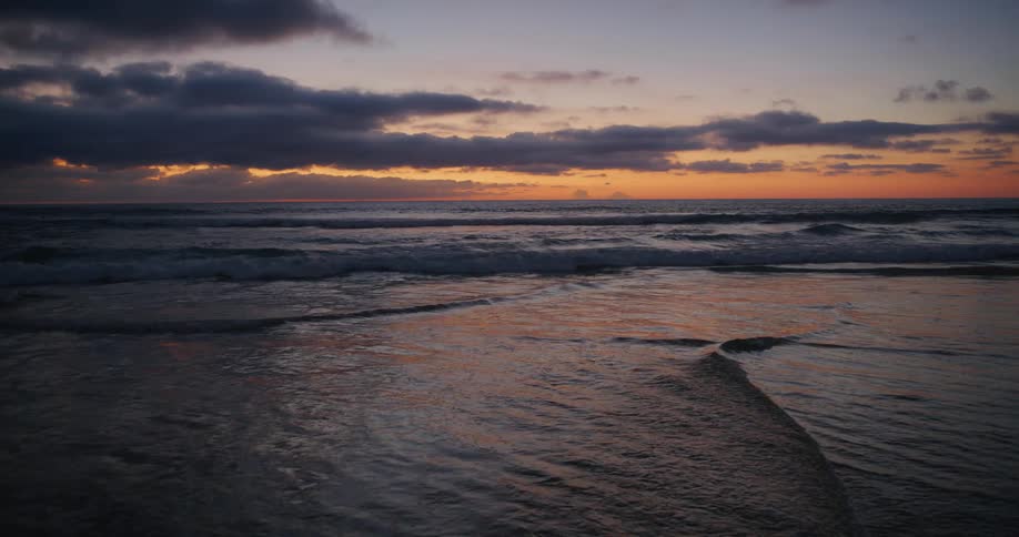 Waves crash on the shore at sunrise