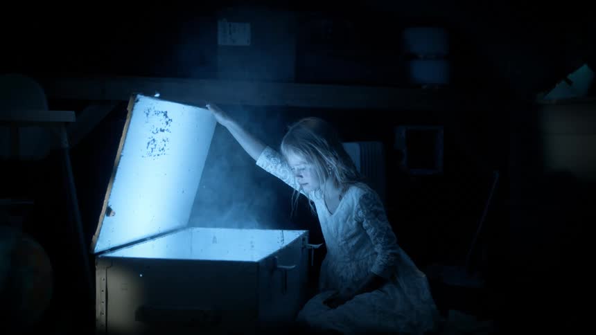 A young stares into a box as smoke rises out of it