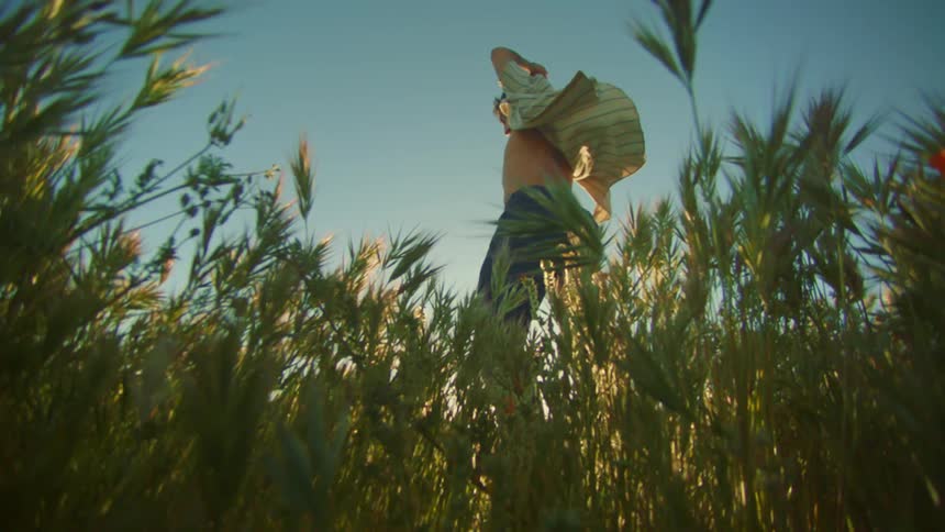 Man wearing an open shirt and dancing while standing in tall grass outdoors