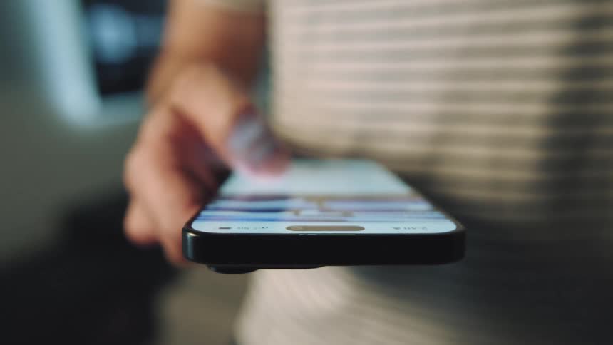 A young man scrolls through a social media feed on his smart phone