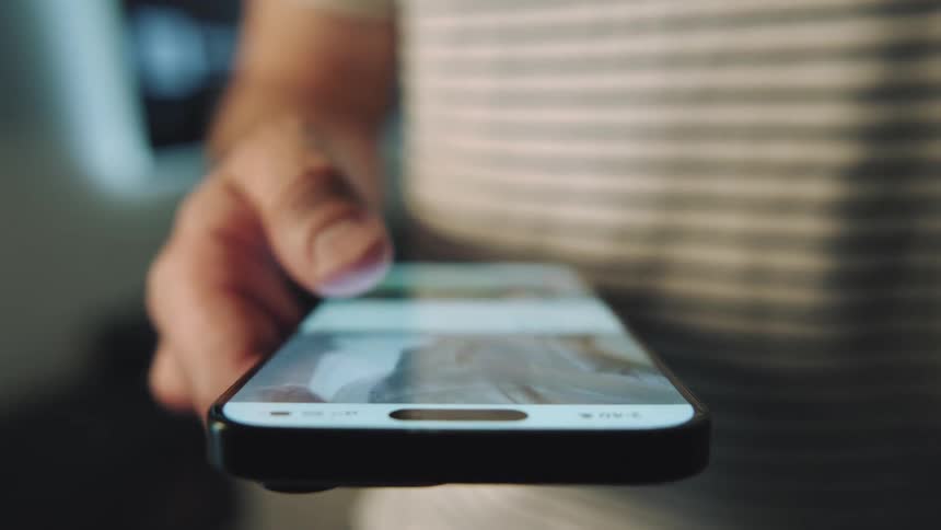 Person hand holding and scrolling finger on smartphone