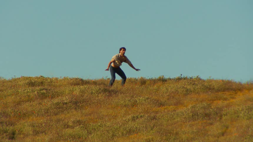 A man dances in slow motion in a field