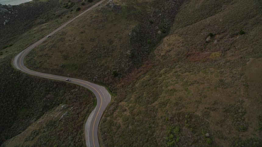 Aerial panorama of a long curving highway through the seaside mountains