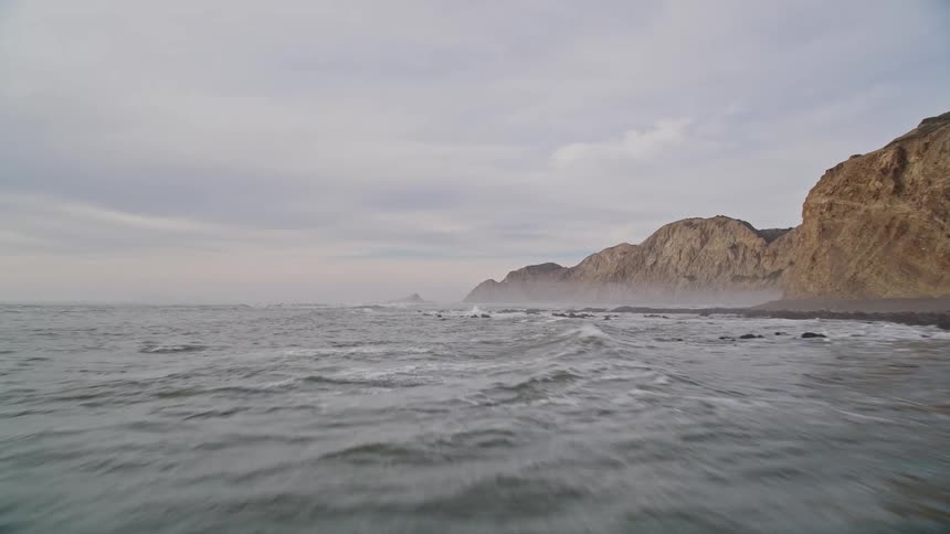 Aerial view of a rocky coastline next to the mountains