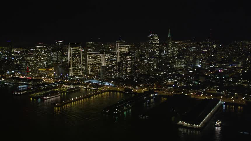 Aerial scenery of a metropolis with a skyscraper illuminated at night and the seaside