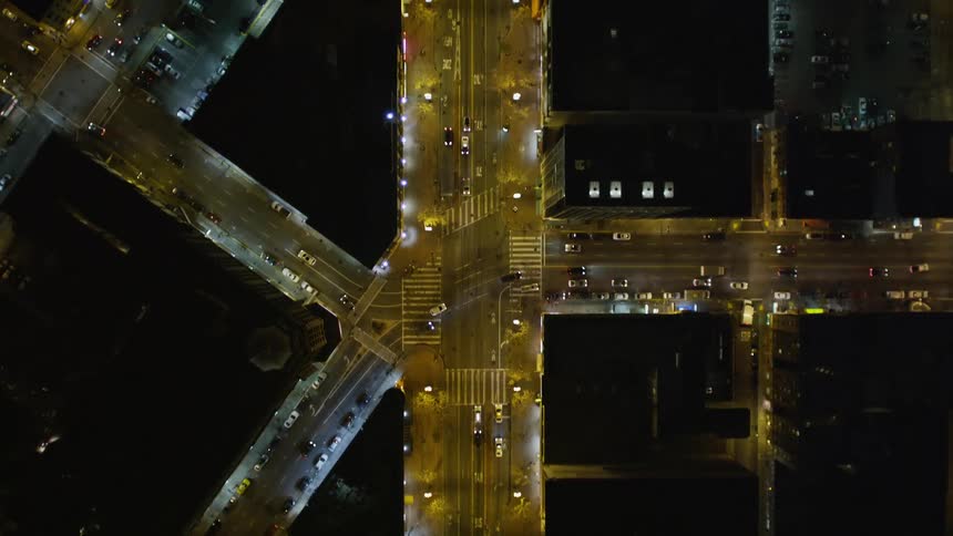 Top view of illuminated buildings at night and intersections with vehicle traffic