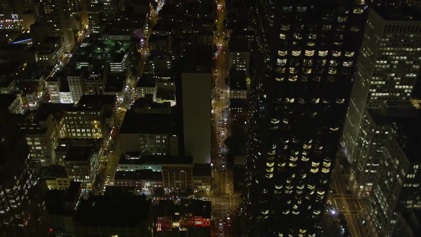 An aerial view of a city with several tall buildings and it is nighttime and several residential lights are on