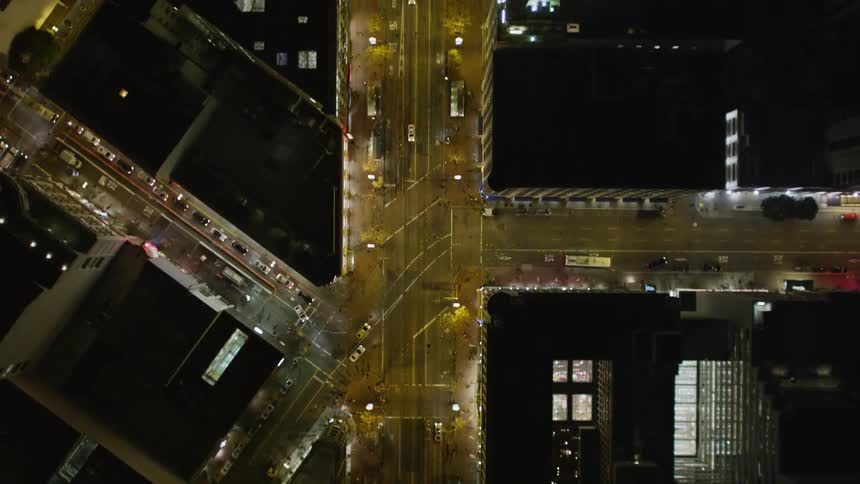 Various vehicles move down a large city street at night