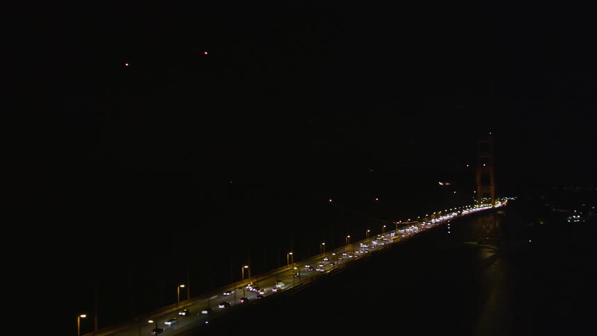 A huge bridge with a freeway on top and many cars passing by at night