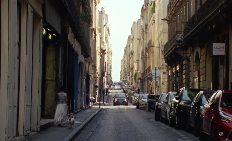 Cars and pedestrians move through a narrow city street