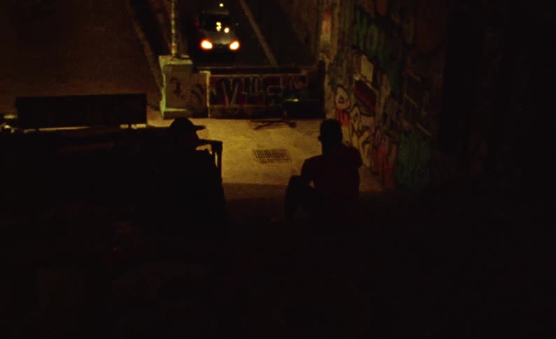 Silhouette of two men sitting on stairs through city streets at night